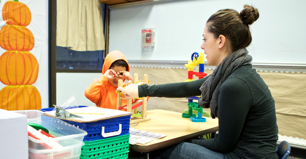 Photo of a child and student teacher working together in the Haring Center.