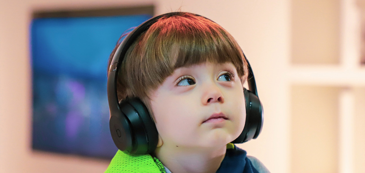 Photo of a young child wearing headphones. Photo by Alireza Attari and Unsplash.