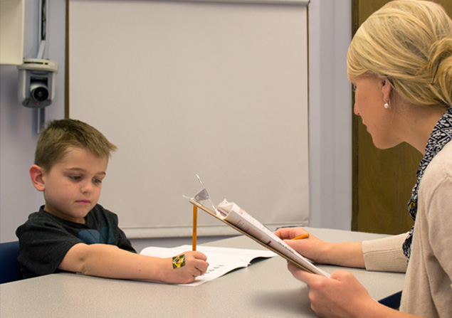 Photo of a young child participating in a behavioral test with a clinic staff member.