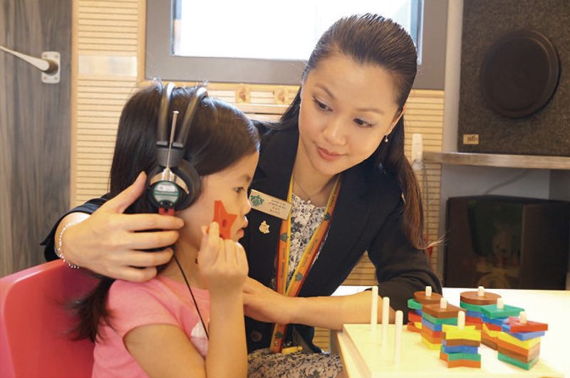 Photo of young child and a clinician performing an audiology test in the Audiology Clinic.