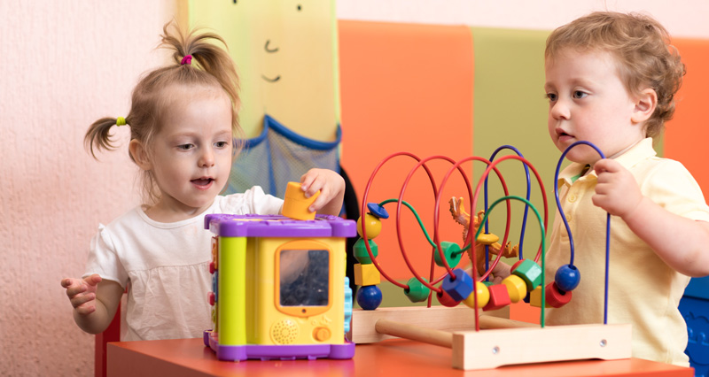 Photo of two kids playing with stocking and sliding block games.