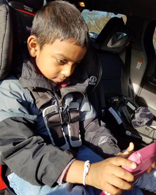 Photo of a child using assistive technology in a car.