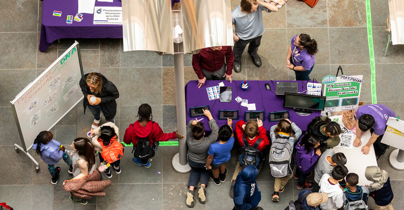 Photo from above of young people visiting a campus fair/event.