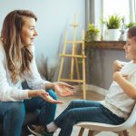 Photo of a clinician interviewing a smiling young patient.