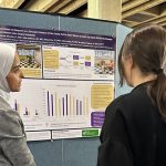 Photo of a Research Day presenter explaining their research project to two people.