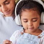 Photo: Mother and child, who is wearing headphones, working on a painting project together.