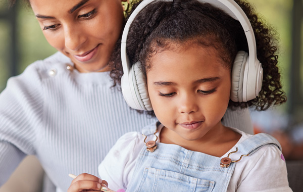 Photo: Mother and child, who is wearing headphones, working on a painting project together.