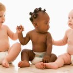 Photo: Three infants wearing diapers sitting on a floor.