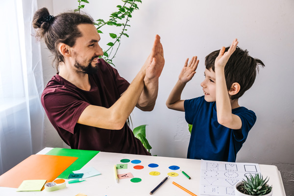 Photo: Teacher and student with autism are smiling and celebrating an achievement.