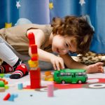 Photo: A young child playing with a toy bus on a play mat.