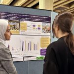 Photo: 2023 Research Day poster presentation by a researcher presenting to two people.