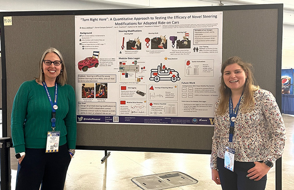 Photo: Assistant Professor Heather Feldner and Mechanical Engineering Grad Student Mia Hoffman standing in front of their Wheels in Motion poster board.