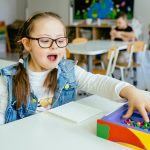 Photo of a child with Down Syndrome playing with blocks in a classroom.