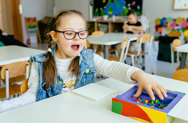 Photo of a child with Down Syndrome playing with blocks in a classroom.