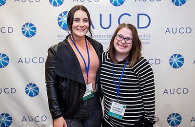 Photo of two smiling attendees at an AUCD Conference.