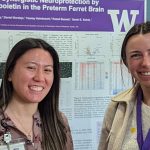 Image: Two 2024 Research Day attendees standing in front of a poster presentation.