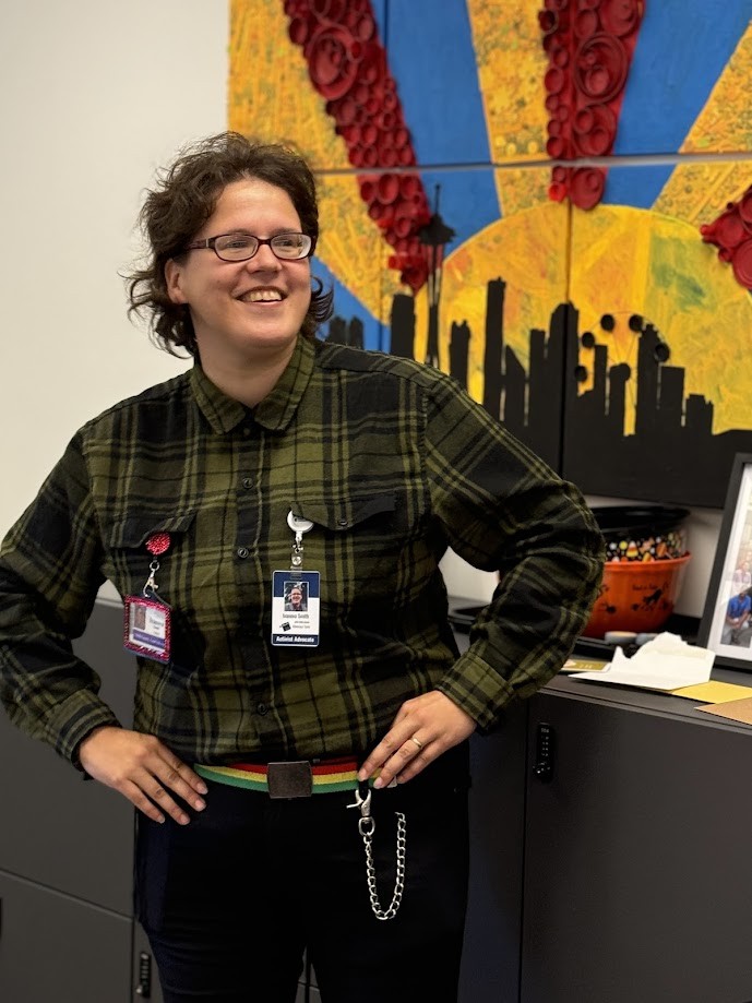 Photo of Ivanova Smith smiling in front of artwork.