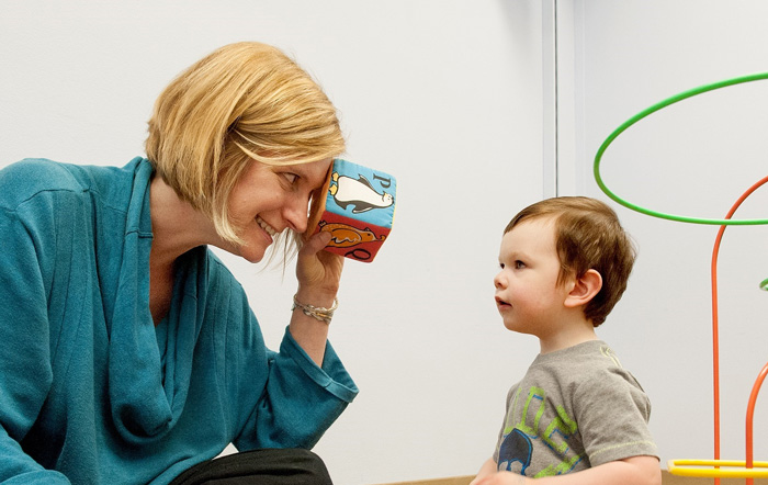 Photo: Dr. Annette Estes smiling and playing with a young student in the UW Autism Center.