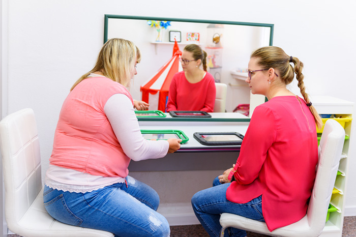 Photo: Instructor teaching a parent how to use an Augmentative Alternative Communication (AAC) device.