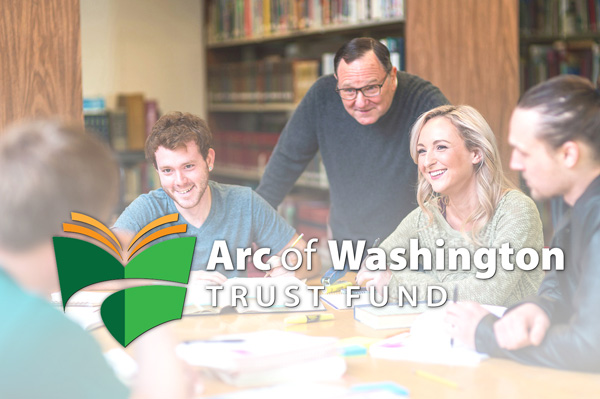 Photo: Group of smiling and sitting at a table during a meeting. The Arc of Washington Trust Fund logo is over the image.