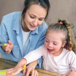 Photo: Smiling parent and child with Down Syndrome finger painting.