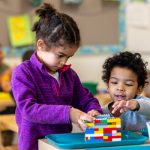 Two children building a Lego structure.