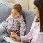 Child and clinician sitting on a couch during an assessment.