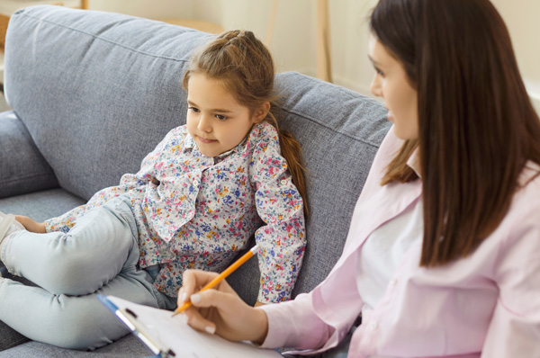Child and clinician sitting on a couch during an assessment.