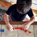 Young child lining up Lego in a straight line on a table.