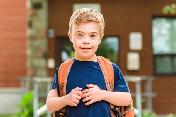 School age child with Down Syndrome wearing a backpack.