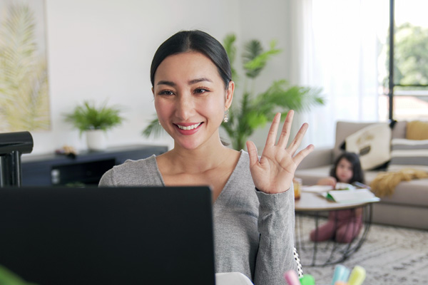 Parent on a Zoom waving while their child plays in the background.