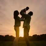 Parents holding young child in the air.