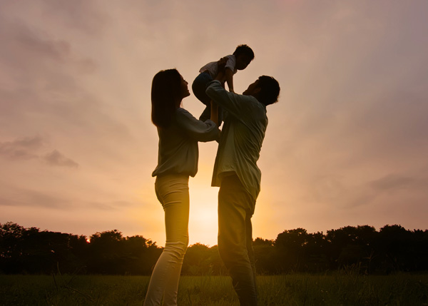 Parents holding young child in the air.