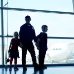 Family at an airport and one child is wearing headphones.