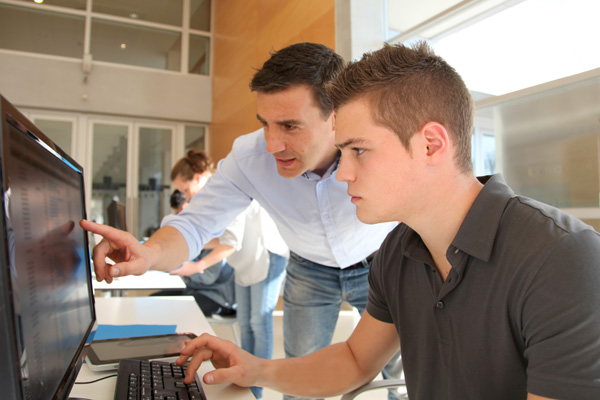 Summer intern working on a computer with a coach.