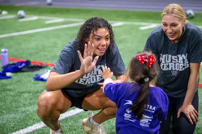 UW student athletes with children at Husky Heroes event.
