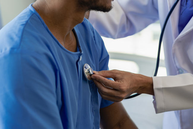 A doctor uses a stethoscope to check the heartbeat of his patient. 