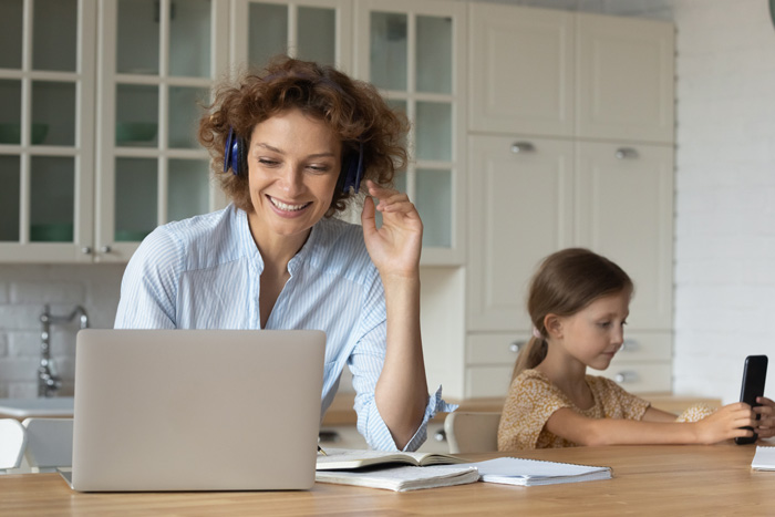 Parent on Zoom call while child is on a mobile device in the background.