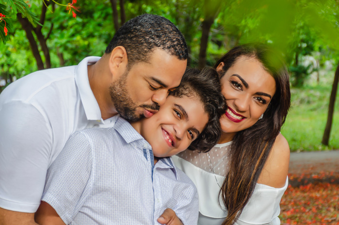Young parents hugging their child and smiling.