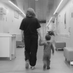 Physician walking a young patient down a hallway.