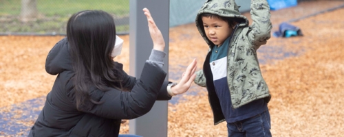 Photo of a teacher and student high-fiving each other on the Haring Center playground.